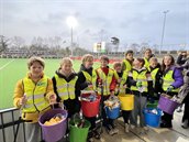 Kinderen in gele hesjes tonen de felgekleurde emmers met opgeruimd afval tijdens de EHL.